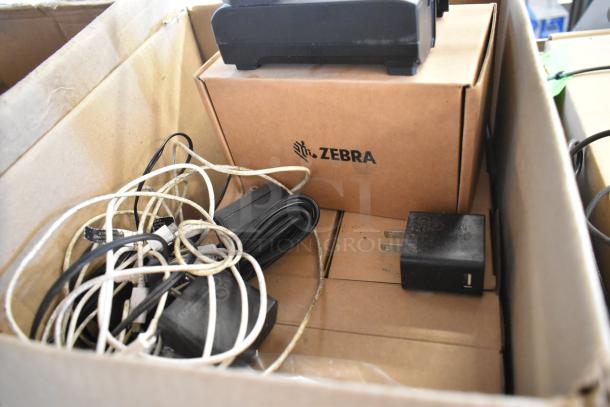 Box of 7 brand new items including Zebra unit, chargers, and wires, with original packaging visible.