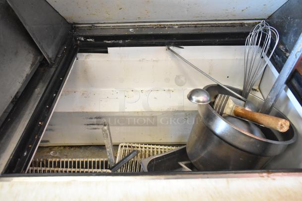 True TSSU-72-30M-S sandwich prep table with utensils inside. Stainless steel, on casters, used condition. Model info visible.