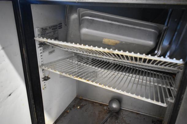 True TSSU-72-30M-S stainless steel prep table interior with wire shelves, commercial casters, and visible label detailing specs.