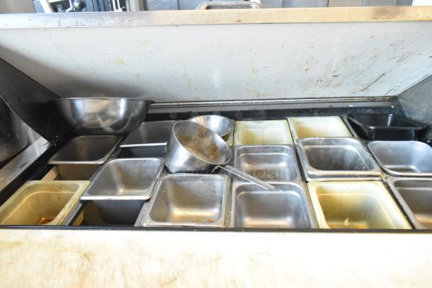 True TSSU-72-30M-B-ST stainless steel sandwich prep table with multiple food pans, commercial casters, used condition.