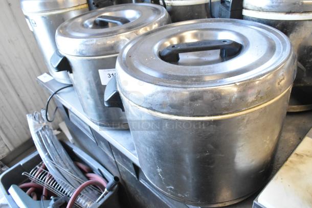 Two large metal rice holders with handles and lids, showing moderate wear, labeled with auction number 312.