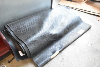 Two brown floor mats featuring a subtle geometric pattern, rolled and stacked, in used condition.