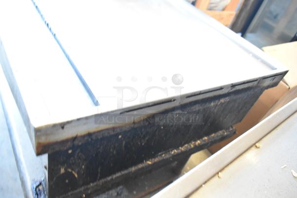 Wolf stainless steel commercial flat top gas griddle on metal stand. Features metal under shelf. Used, visible wear.