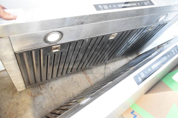Stainless steel range hood with baffle filters, built-in lights, and digital controls, showing signs of use.