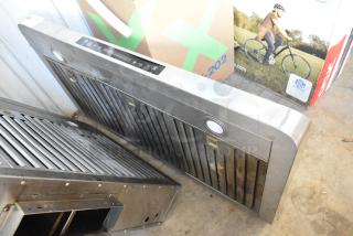 Stainless steel metal range hood with dual filters and control panel. Some visible wear; integrated lights included.