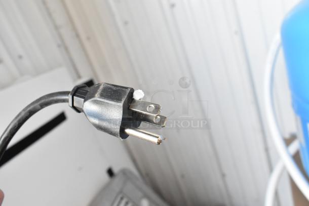 Close-up of a three-prong electrical plug, part of a metal range hood, indicating a standard power connection.