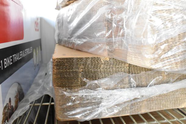 Four brand new bundles of corrugated cardboard wrapped in plastic, showcasing layered texture and pristine condition.