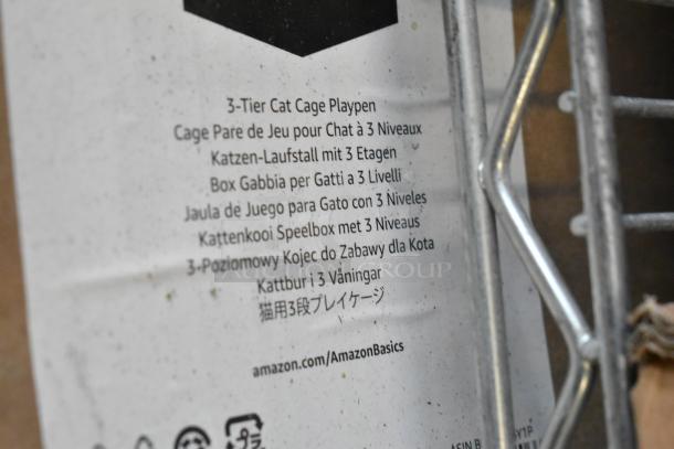 Brand new black 3-tier cat cage playpen, AmazonBasics. Multilingual label visible, indicating high versatility.