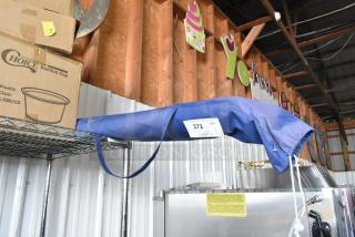 Blue and white canopy in storage, number 372. Slight wear visible. Auction tag present for identification.
