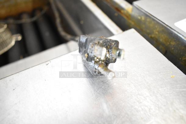 Close-up of a worn plug on a stainless steel surface, part of the Pitco Frialator SSH75 commercial deep fat fryer.