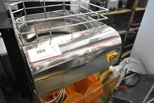 Metal commercial citrus juicer, countertop model, 115 volts, 1 phase. Features steel body and protective grill. Auction tag "389" visible.