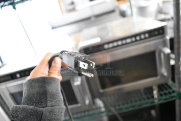 A hand holding a power plug for a commercial countertop citrus juicer, 115 volts, 1 phase.