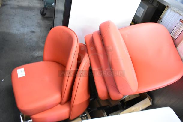 Five brand new red bucket seat style stool seats, no frames, stacked together. Identifiable tag visible on one seat.