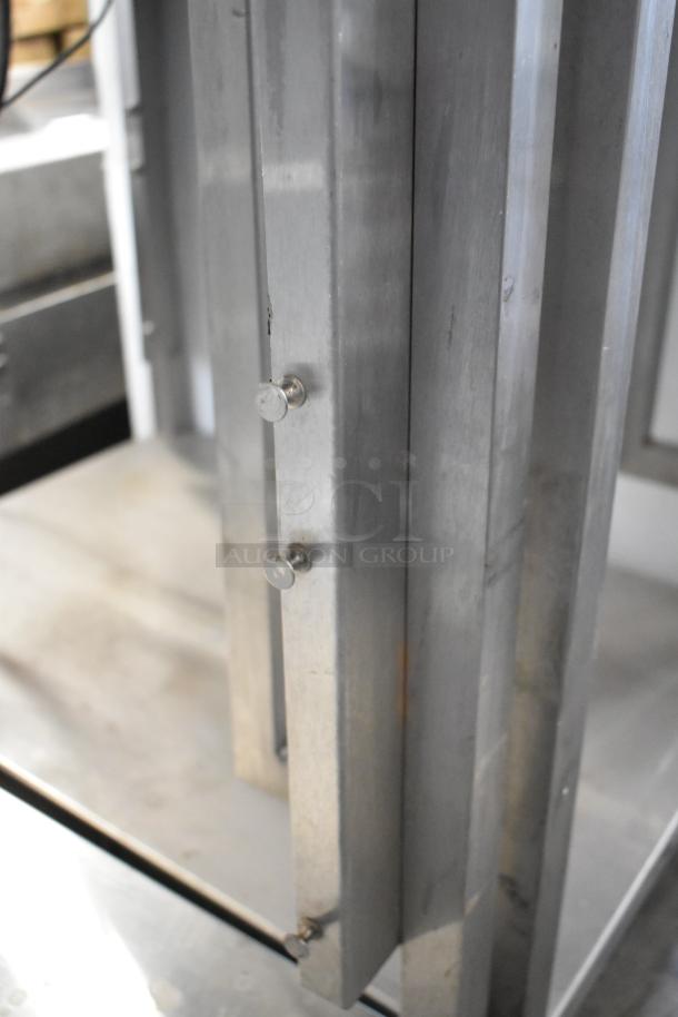 Stainless steel metal table with under shelf, sturdy frame, visible screws, good condition for industrial use.