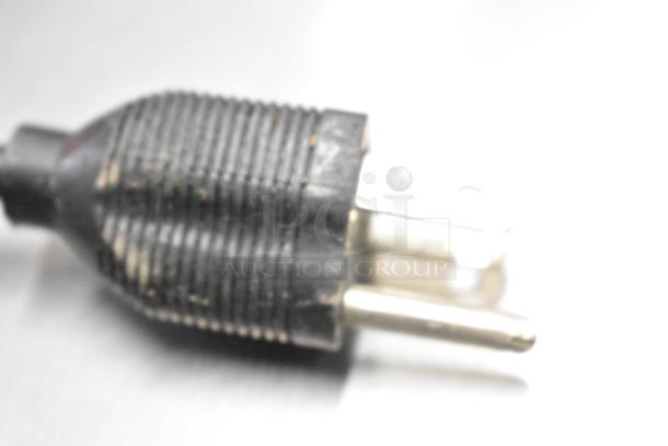 Blurred close-up of a power plug, likely part of the 2023 Hobart HTi commercial food portioning scale.