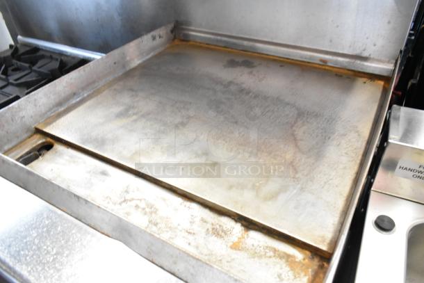 Imperial stainless steel commercial gas range with 6 burners, right side flat top griddle, 2 ovens, over shelf, backsplash, and casters.