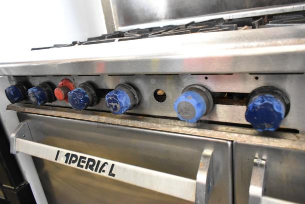 Imperial stainless steel commercial gas range with 6 burners, right flat top griddle, 2 ovens, overshelf, and backsplash.