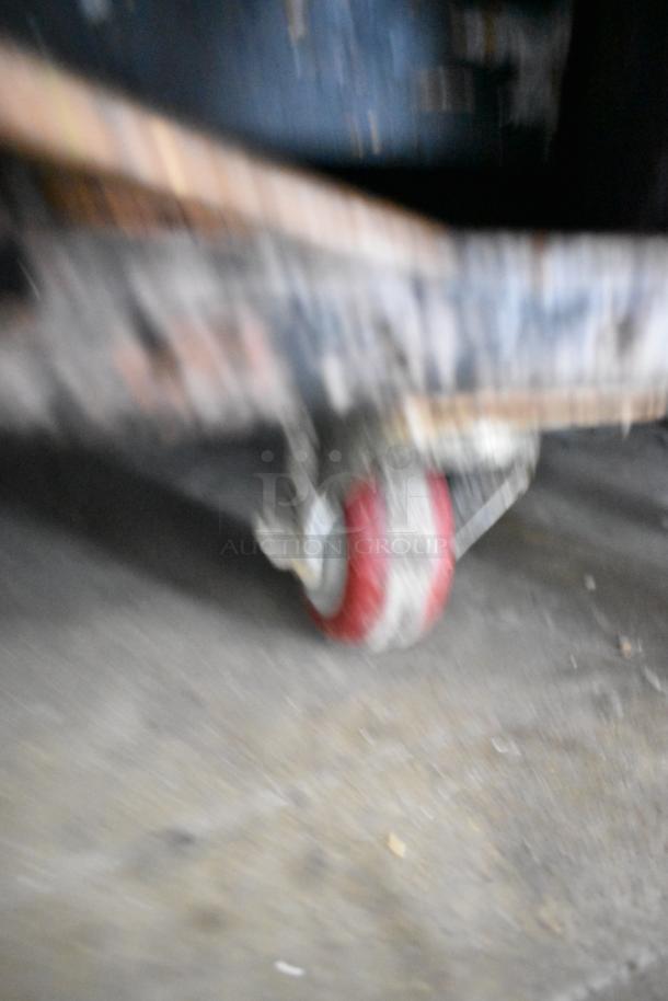 Blurred image of a red caster wheel beneath a commercial appliance, indicating mobility.