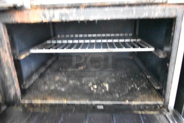 Commercial gas range with 6 burners, flat top griddle, 2 ovens, over shelf, backsplash, stainless steel; used condition.