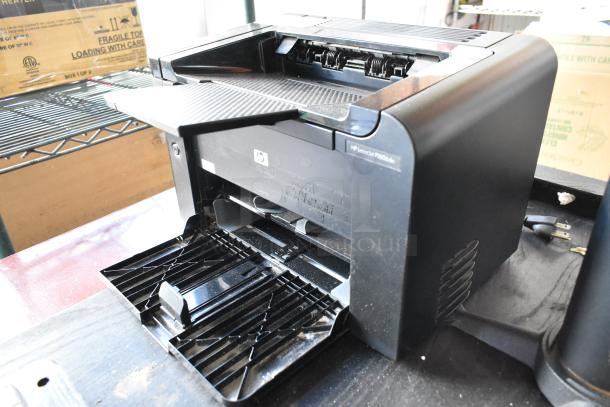 HP LaserJet P1606dn countertop printer, black, visible open tray, moderate wear, power cord included.