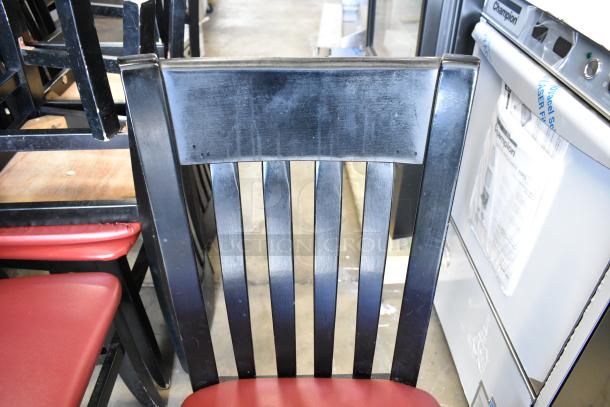 Black dining chair with red seat cushion, featuring a slatted backrest. Good condition. Auction includes 14 chairs.