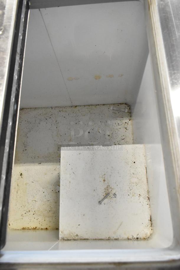 Kelvinator commercial chest freezer interior, showing wear and dirt. Features metal build, on casters, 115V, 1 phase.