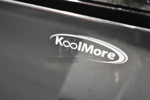 KoolMore logo on metal surface of commercial countertop merchandising case; slight visible damage present.