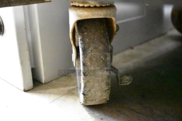 Close-up of a commercial caster on the True TSSU-48-12 stainless steel prep table, showing wear.