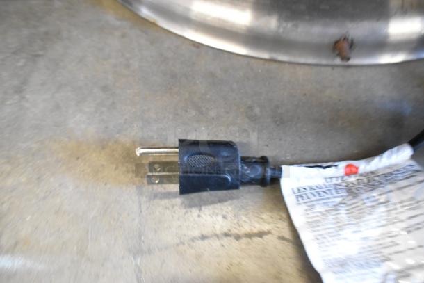 Electric plug and cord for a metal round chafing dish; visible attached label with instructions.