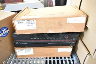 Four brand new items including Dahua network video recorders, in original packaging, featuring control buttons and USB ports.