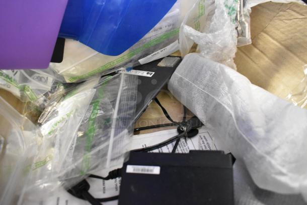 Lot of various items including plastic bags, electronics, and cables with some labels visible. Mixed condition.