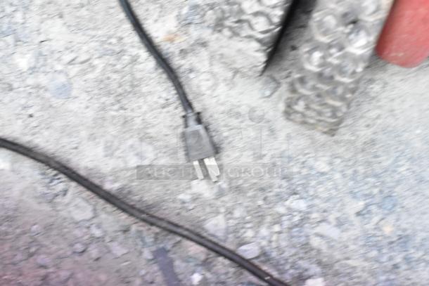 Blurry image showing a power plug on a rough surface. Not directly showcasing the General Electric GE FCM75UBWW Chest Freezer.