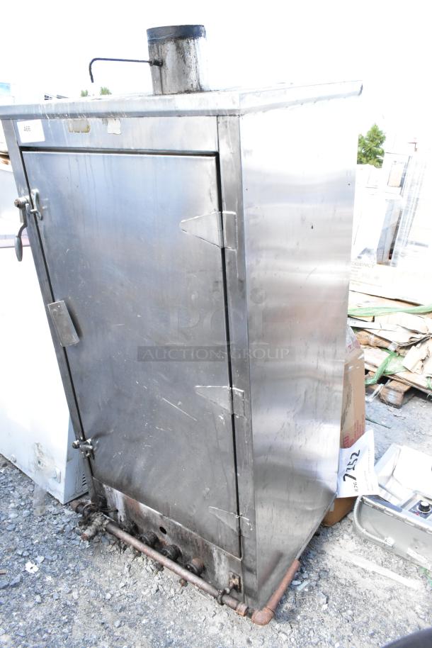 Metal commercial gas-powered vertical Chinese smoker, used condition, stainless steel, with visible smoke stack and latching door.