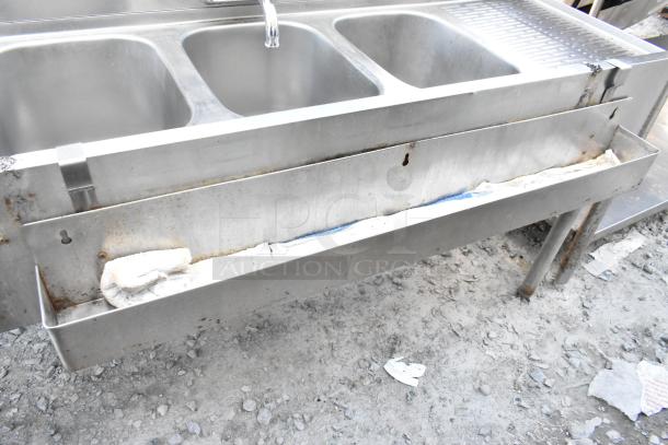 Stainless steel 3 bay back bar sink with dual drain boards and speewell, showing signs of wear and rust.