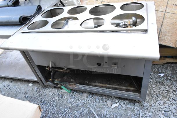 Stainless steel commercial steam table with six compartments, showing some wear. Ideal for catering or restaurant use.