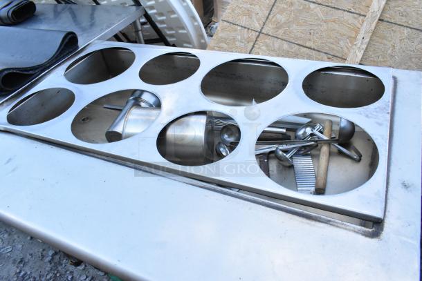 Stainless steel commercial steam table with multiple circular compartments, utensils visible, in fair condition.