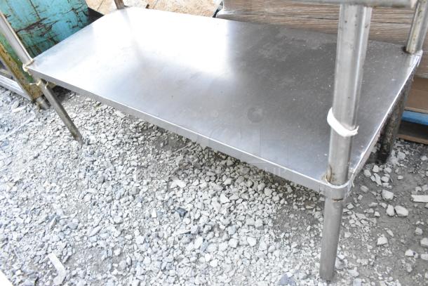 Stainless steel table with under shelf, sturdy metal construction, used condition, suitable for industrial use.
