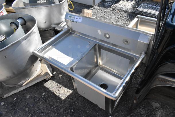 Brand new Regency 600S1181818L stainless steel single bay sink with left side drain board, no legs, minor dents visible.