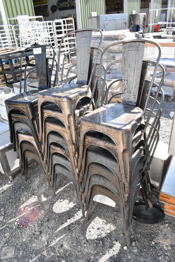 Stack of 19 brand new Tolix style metal chairs, rustic finish with visible scratches and dents, outdoor setting.