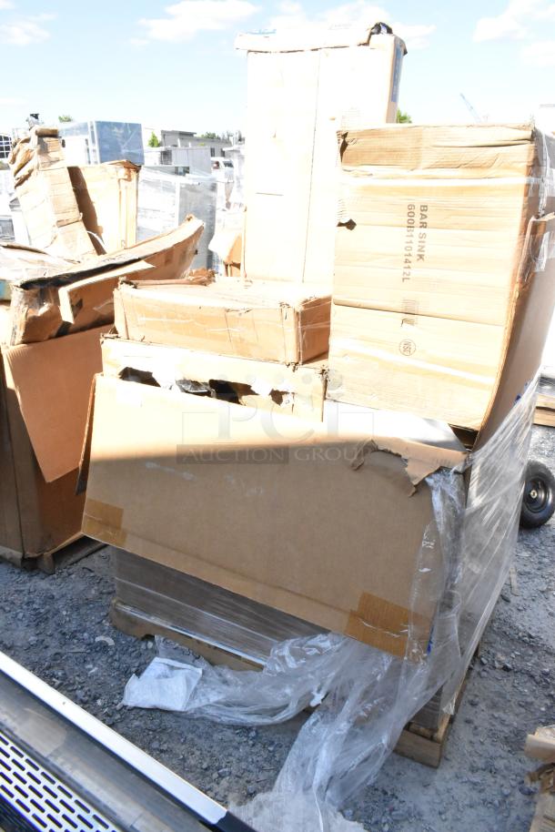 Damaged boxes containing new scratch and dent items, including a Fetco coffee dispenser and Regency sink, stacked on a pallet.