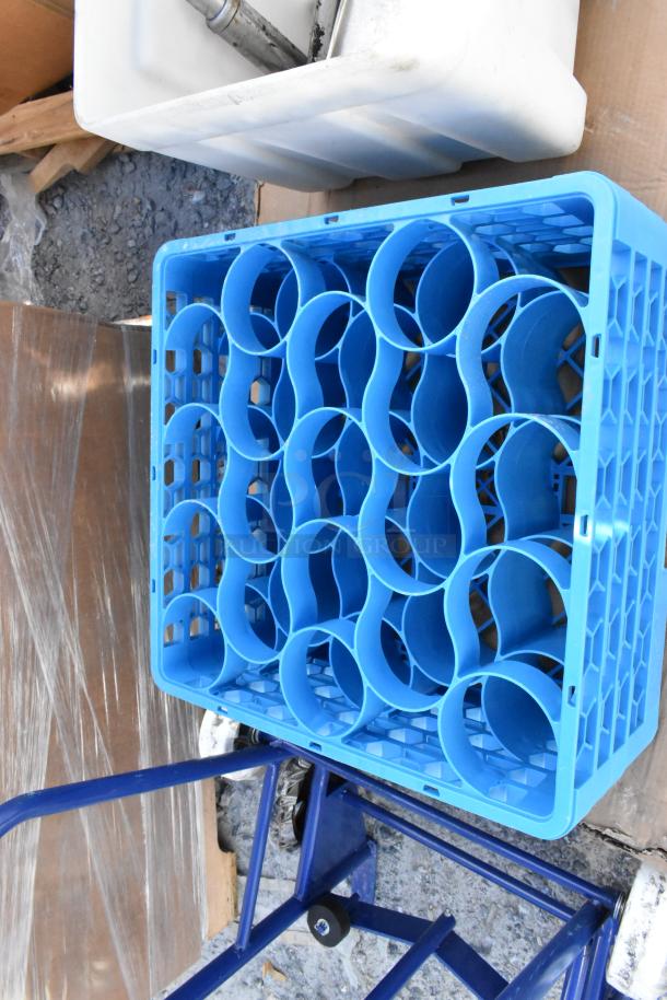 Blue plastic receptacle crate with circular compartments, placed on a metal dolly outdoors, part of auction lot.