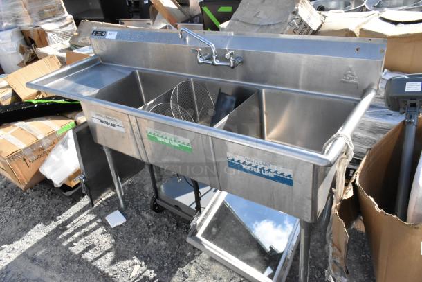 Stainless steel 3-bay sink with left side drain board, labeled "Aero." Features include faucets and visible "Water Line" markings.