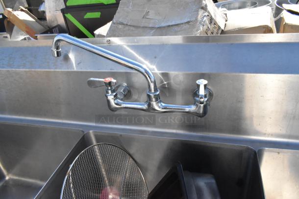 Stainless steel 3 bay sink with left side drain board, featuring dual faucet controls. Good condition.