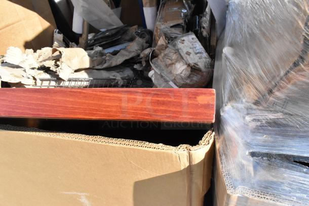 Cardboard box containing mixed scratch and dent items, including Tolix-style metal chairs, partially visible with packing material.