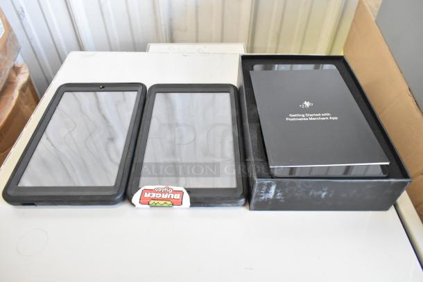 3 tablets in protective cases, one with "Burger Blip" label, and another boxed with Postmates Merchant App guide.