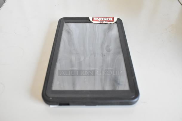A tablet with a black frame resting on a surface. The label "Burger Bytes" is visible at the top edge.