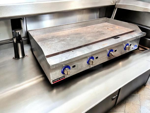 Globe 4-burner gas griddle in excellent condition. Stainless steel, fully tested, Chef's Toys label visible.