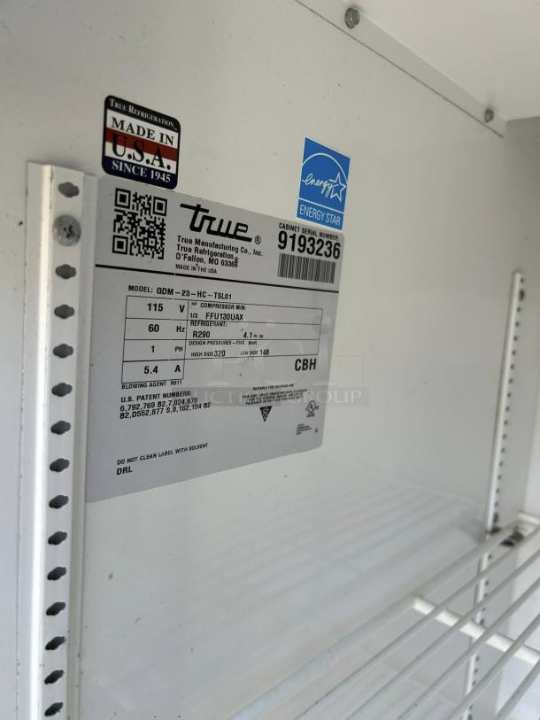 Label inside a True GDM-23-HC~TSL01 merchandiser. Features model, voltage, compressor, refrigerant, and serial number. Tags indicate "Made in USA" and "Energy Star."