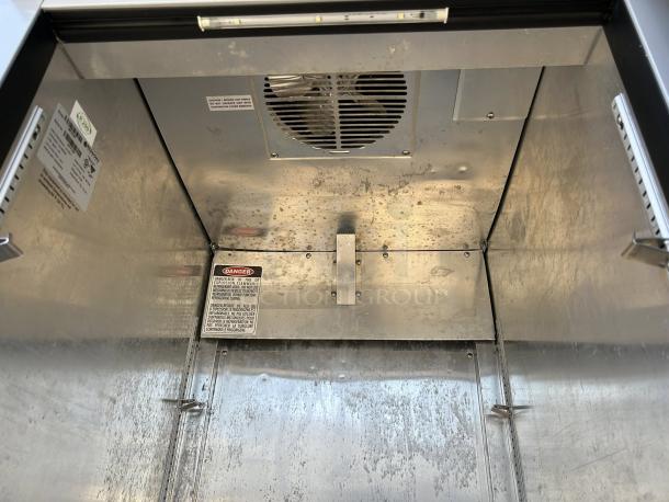 Economy Series EF1A-FS single door commercial freezer interior, showcasing shelving brackets and safety labels, excellent condition.