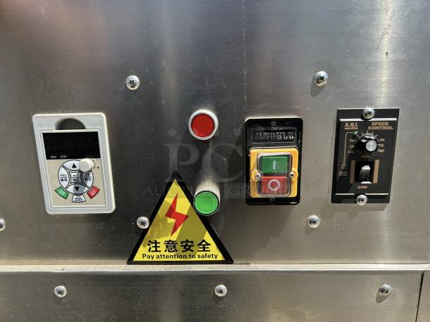 Industrial control panel with buttons and speed control, featuring a safety warning label in Chinese and English. In working condition.